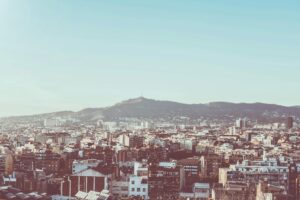 A panoramic view of Barcelona's urban landscape with Montjuïc in the background under clear skies.