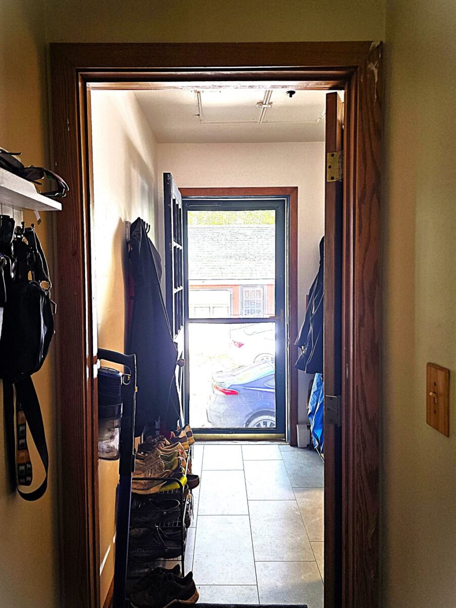 A mirror image of the first, showing the same mudroom and front door, though straightened and flooded with color of the bright, natural sunlight.