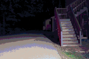 A set of wooden stairs at night leading into a building, the rest of the image is of a road leading into darkness. Image has been heavily compressed.
