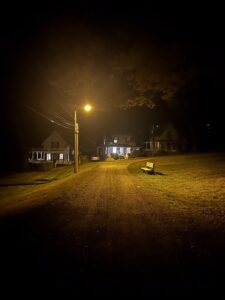 A lonely park bench underneath a streetlight