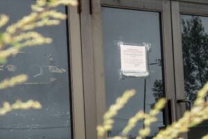 A 20th-century storefront with a condemnation notice taped to the glass of the door.