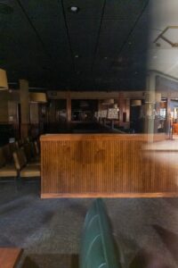 A view of the dark interior of a closed restaurant through the glass of one of its windows