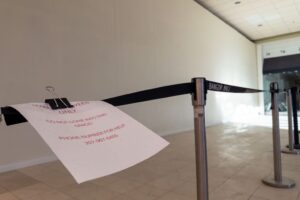 A barricade belt in front of a walled-off area indoors, bearing a paper note warning the section is employees-only