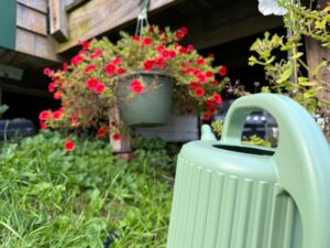 a watering can infront of a hanging flower basket